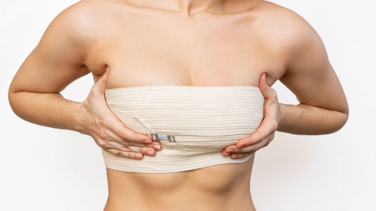 Mulher segurando os seios em meio a recuperação da mamoplastia redutora