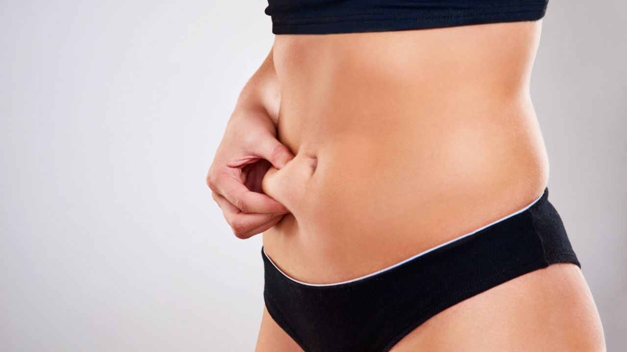 Zoom de mulher apalpando pouca porção de gordura localizada de sua barriga